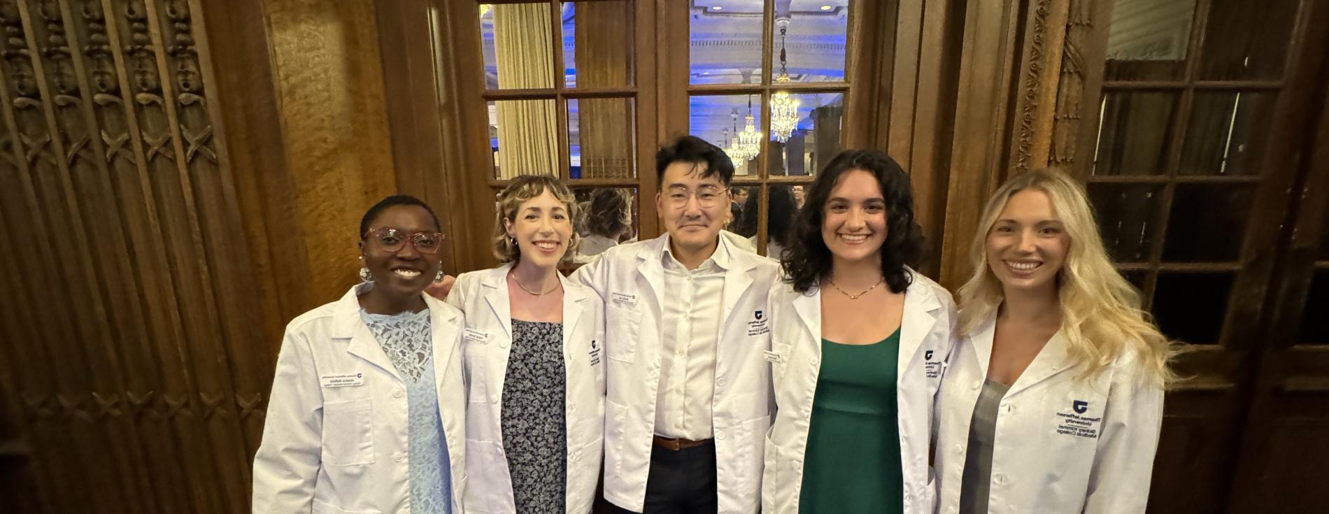 Group of smiling students wearing med student white coats